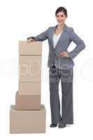 Serious businesswoman with cardboard boxes on her side