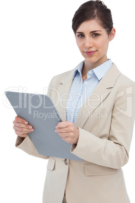 Serious businesswoman with clipboard and looking at camera