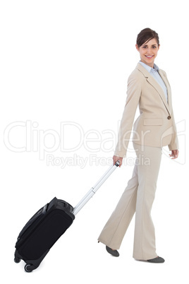 Smiling businesswoman pulling suitcase