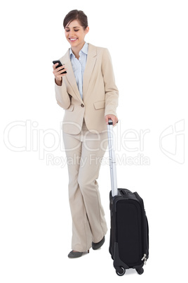 Cheerful businesswoman with suitcase and phone