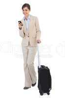 Cheerful businesswoman with suitcase and phone