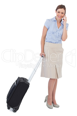 Cheerful classy businesswoman with suitcase and phone