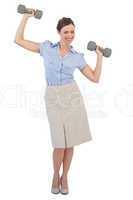 Strong businesswoman lifting dumbbells looking at camera