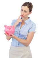 Thoughtful businesswoman with piggy bank
