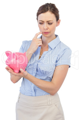 Pensive businesswoman with piggy bank