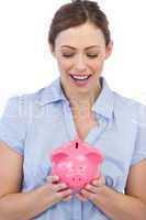 Astonished businesswoman posing with piggy bank