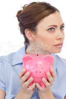 Thoughtful businesswoman posing with piggy bank in close up