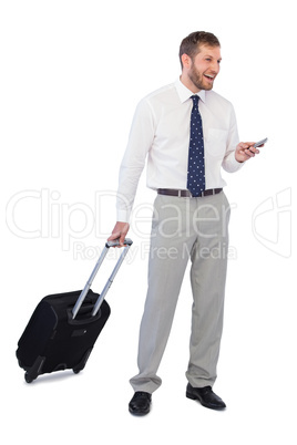 Wide smiling businessman with phone and suitcase