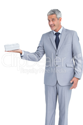 Handsome businessman holding gift and looking at camera