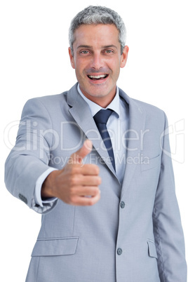 Cheerful businessman looking at camera reaching for handshake