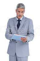 Serious businessman using tablet pc looking at camera