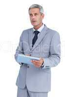 Serious businessman using tablet pc looking away