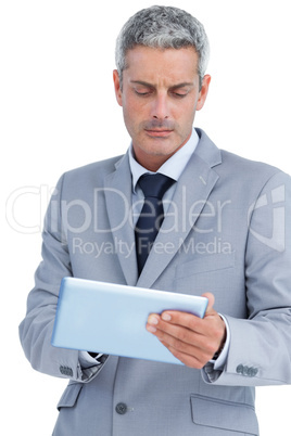 Frowning businessman using digital tablet