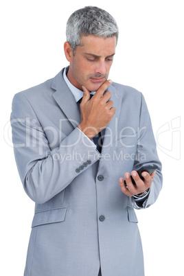 Thoughtful businessman touching his chin and looking at his phon