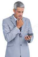 Thoughtful businessman touching his chin and looking at his phon
