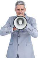 Furious businessman posing with loudspeaker and looking at camer