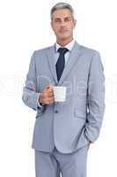 Serious businessman standing with coffee