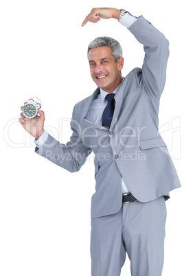 Cheerful businessman pointing out alarm clock