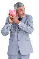 Curious businessman holding piggy bank