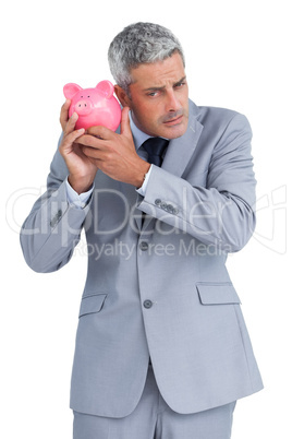 Sceptical businessman holding piggy bank