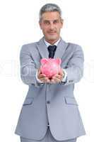 Confident businessman holding piggy bank in both hands