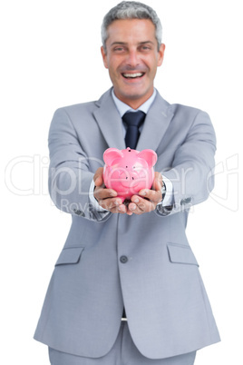Wide smiling businessman holding piggy bank