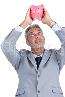 Curious businessman holding piggy bank above his head