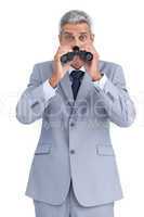 Curious businessman observing with binoculars