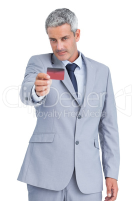 Handsome businessman holding and looking at credit card