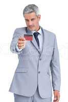 Handsome businessman holding and looking at credit card