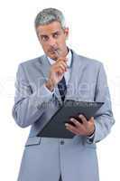 Pensive businessman holding clipboard and taking notes