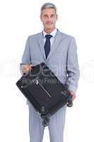 Handsome businessman carrying suitcase and looking at camera