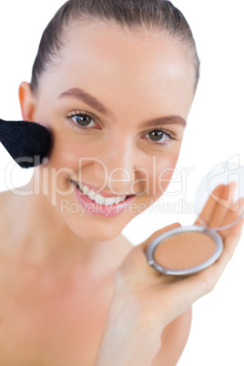 Cheerful young model applying face powder
