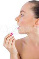 Profile of woman putting lip gloss on her lips
