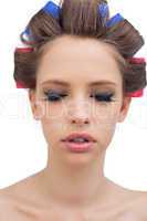 Pretty model with hair curlers closing eyes