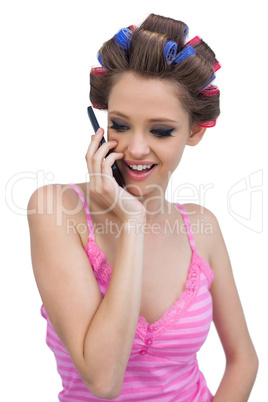 Happy model wearing hair rollers having a call