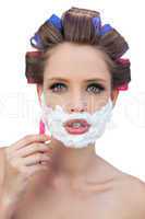 Young model in hair curlers posing with shaving foam and razor