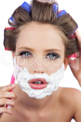 Model in hair curlers posing with shaving foam and razor in clos