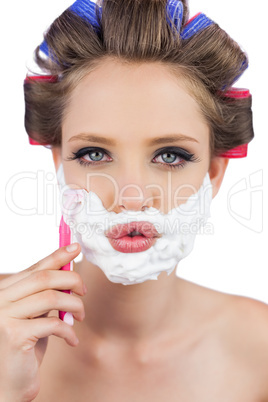 Sexy young model in hair curlers posing with razor