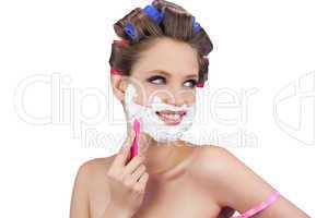 Cheerful lady in hair curlers posing with razor