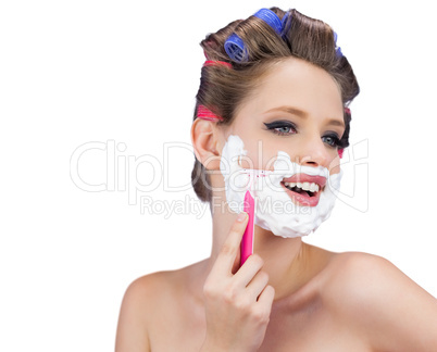 Happy model in hair curlers posing with razor