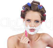 Delightful model in hair curlers posing with razor