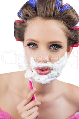 Young model in hair curlers posing with razor