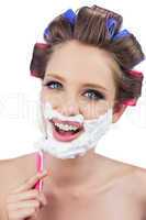 Smiling model in hair curlers posing while shaving
