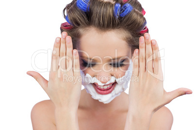 Pensive woman with hands up and shaving foam on face