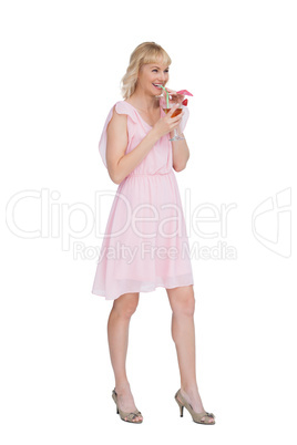 Cheerful blonde posing while drinking cocktail