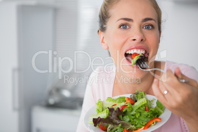 Casual blonde posing while eating salad