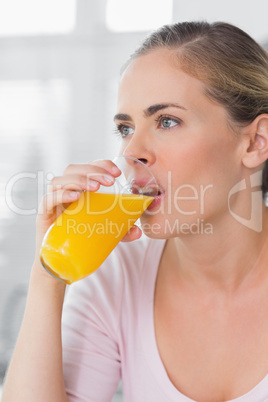 Thoughtful woman drinking orange juice