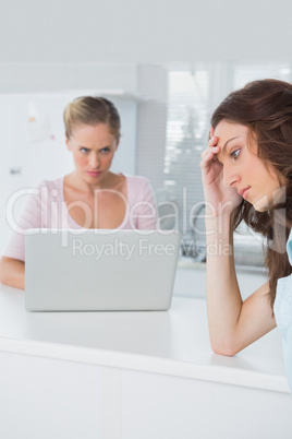 Upset woman thinking while her angry friend is looking at her