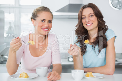 Cheerful friends eating cake and having coffee